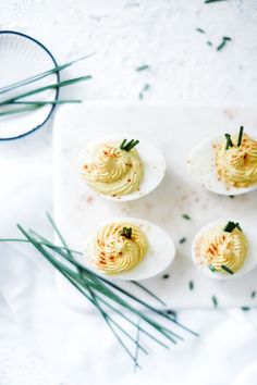 four deviled eggs on a white plate with green sprigs next to them