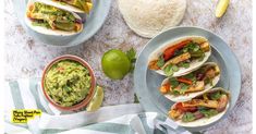 an overhead view of tacos and guacamole with limes on the side