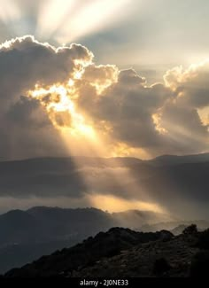 the sun shines through clouds over mountains and valleys on a cloudy day in this photo