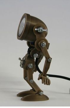 a wooden robot lamp on a white surface with a black cord connected to it's head