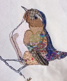 an embroidered bird sitting on top of a piece of cloth with stitches all over it