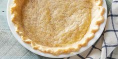 a pie sitting on top of a white plate next to a blue and white towel