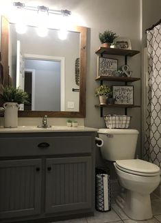 a white toilet sitting next to a sink in a bathroom under a mirror with shelves above it