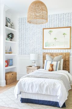 a bedroom with blue and white wallpaper, wicker headboard, rattan basket hanging over the bed