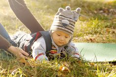 a baby wearing a hat laying on the ground