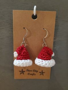 a pair of red and white crocheted santa hat earrings on a brown card