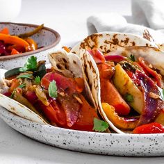 three tacos are sitting in a bowl on the table