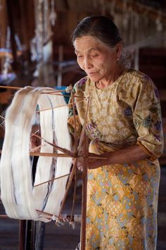 an old woman weaving fabric on a loom