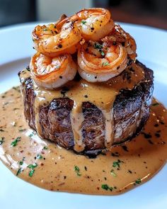 a steak covered in shrimp and sauce on a plate