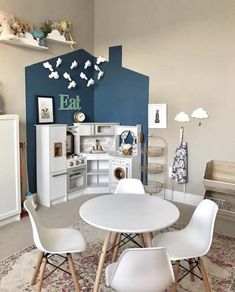 a small child's playroom with white furniture and blue walls, including a table and chairs