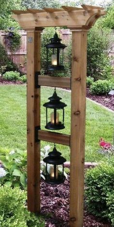 a wooden structure with lanterns hanging from it's sides in the middle of a garden