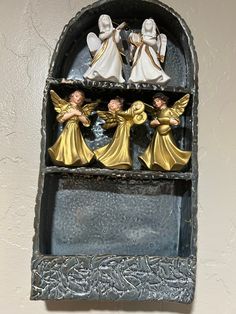 three angel figurines are sitting on a shelf in the shape of an arch