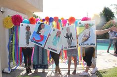 some people holding up pictures and balloons in front of a fence with pom poms