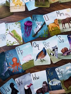 several cards with animals and letters on them sitting on top of a wooden table next to each other