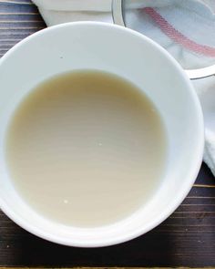 a white bowl filled with liquid on top of a wooden table