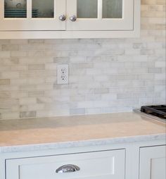 a kitchen with white cabinets and marble counter tops