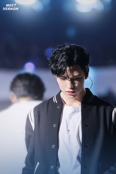 a young man wearing headphones standing in front of a stage with lights behind him