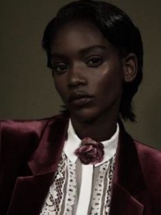 a woman wearing a red jacket and white shirt with a flower in her lapel