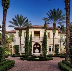 a large white house with lots of trees and bushes around it's entrance area