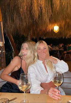 two women sitting at a table with wine glasses