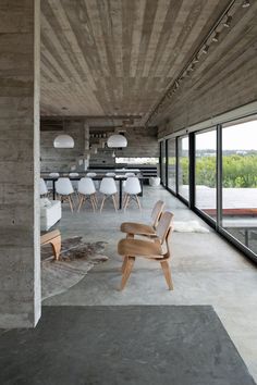 an empty room with chairs and tables in the center, along with large windows on both sides