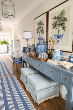 a blue and white entryway with artwork on the wall, bench and stools