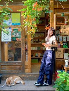 a woman standing in front of a store next to a dog laying on the ground