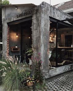 the outside of a restaurant with plants and potted plants