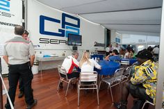 several people sitting at tables in front of a wall with a sign that says ces