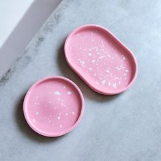 two pink dishes sitting on top of a counter