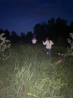 two people walking through tall grass at night