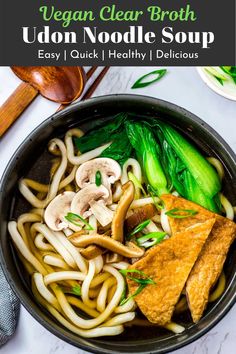 vegan clear broth udon noodle soup in a black bowl with vegetables