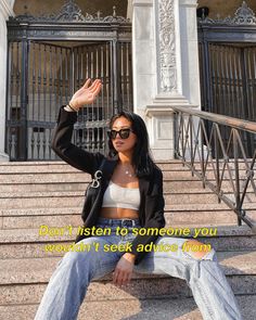 a woman sitting on some steps with her hand in the air