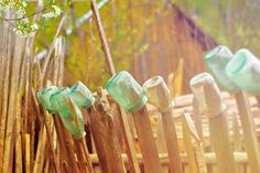 there are many empty glass bottles on the wooden fence, all lined up in a row