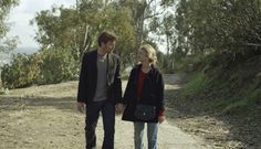 a man and woman walking down a dirt road