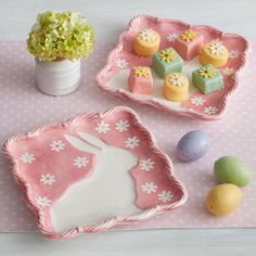 two trays filled with different types of cakes on top of a pink table cloth