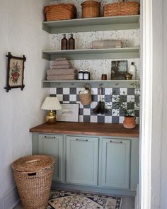 a kitchen with green cabinets and baskets on the shelves above it, along with a rug