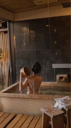 a woman is sitting in the bathtub with her hair hanging back and looking into the mirror