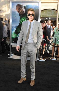 a man in a suit and sunglasses standing on a black carpet at the movie's premiere