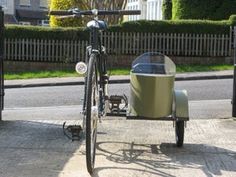 a bike with a cooler attached to it parked on the side of the road next to a fence