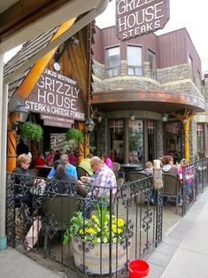 people sitting at tables in front of a restaurant