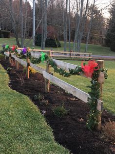 a wooden fence decorated with christmas decorations and lights in the grass next to a field