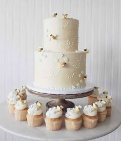 a wedding cake and cupcakes on a table