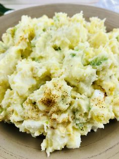 a white plate topped with mashed potatoes and broccoli covered in seasoning