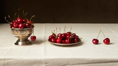 cherries in a bowl on a table with other cherries around the bowl and plate