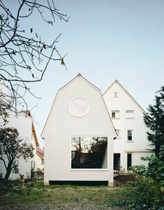 a white house sitting in the middle of a field next to some trees and bushes