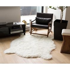 a living room filled with furniture and a white rug on top of a hard wood floor