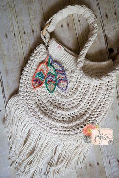 a crocheted purse with colorful beads and fringes on the handle sits on a wooden floor