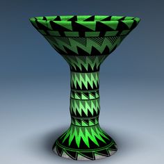 a green and black vase sitting on top of a table