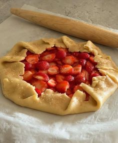 a pie crust with strawberries on it and a rolling pin